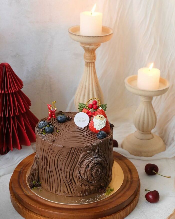 Christmas snack idea: Yule log cake with berries, Santa decoration, candles, and festive decor.