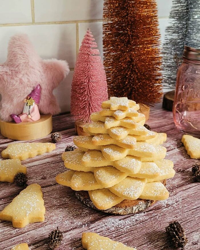 Christmas snack food ideas with cookies shaped like a tree, dusted with powdered sugar, surrounded by festive decorations.