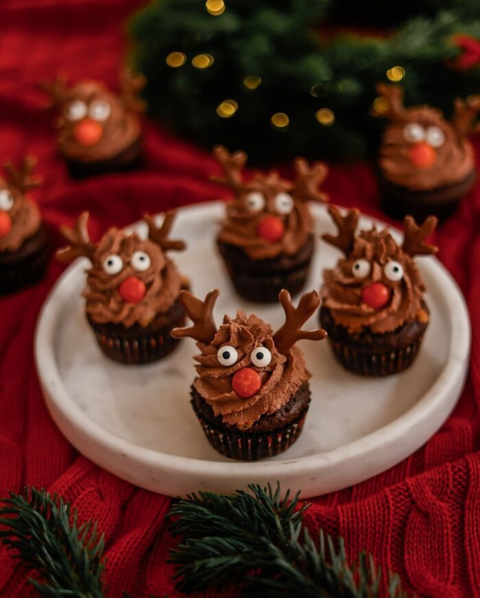 Reindeer cupcakes on a plate, surrounded by festive Christmas decor. Perfect Christmas snack food idea.