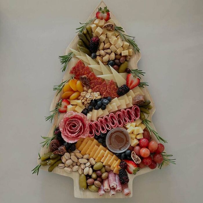 Christmas snack food ideas with a festive tree-shaped platter of cheeses, fruits, nuts, and cured meats.