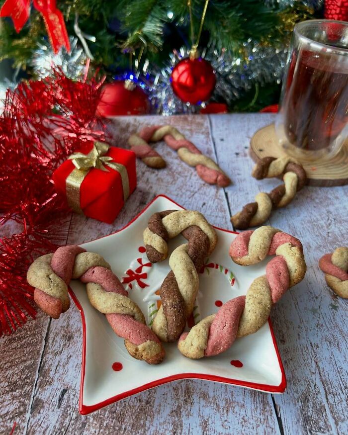 Festive twisted cookies on a star-shaped plate with Christmas decorations and a gift box. Perfect Christmas snack food ideas.