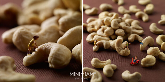 Miniatures of people and vehicles creatively arranged on large cashew nuts, depicting a tiny world of foods and things.