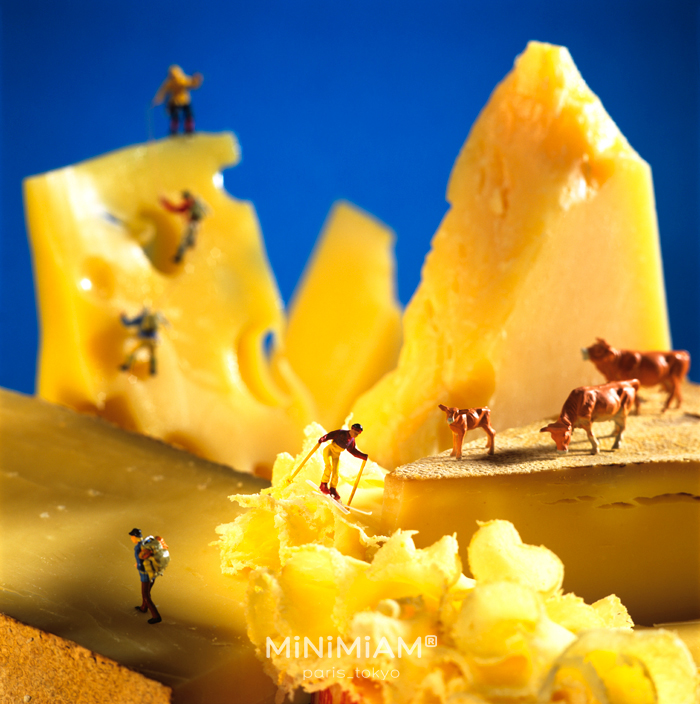 Miniature figures exploring a cheese landscape, representing the tiny world of foods.