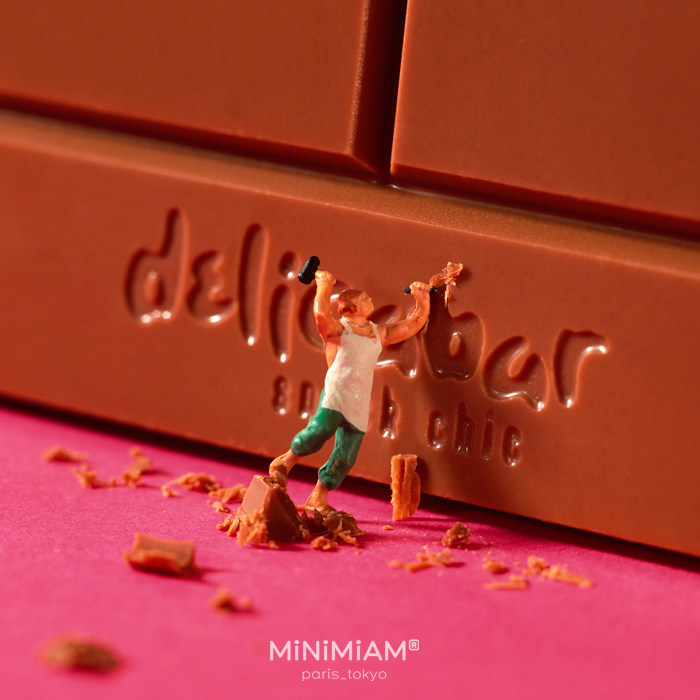 Miniature figure carving chocolate with a tiny hammer, showcasing the creative duo's tiny world of foods and things.