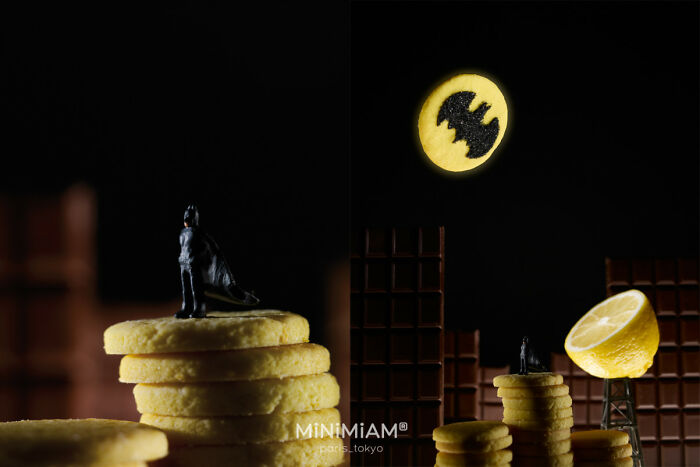 Miniature scene with figure on cookie stacks, lemon slice as bat-signal, and chocolate bar buildings in tiny world.