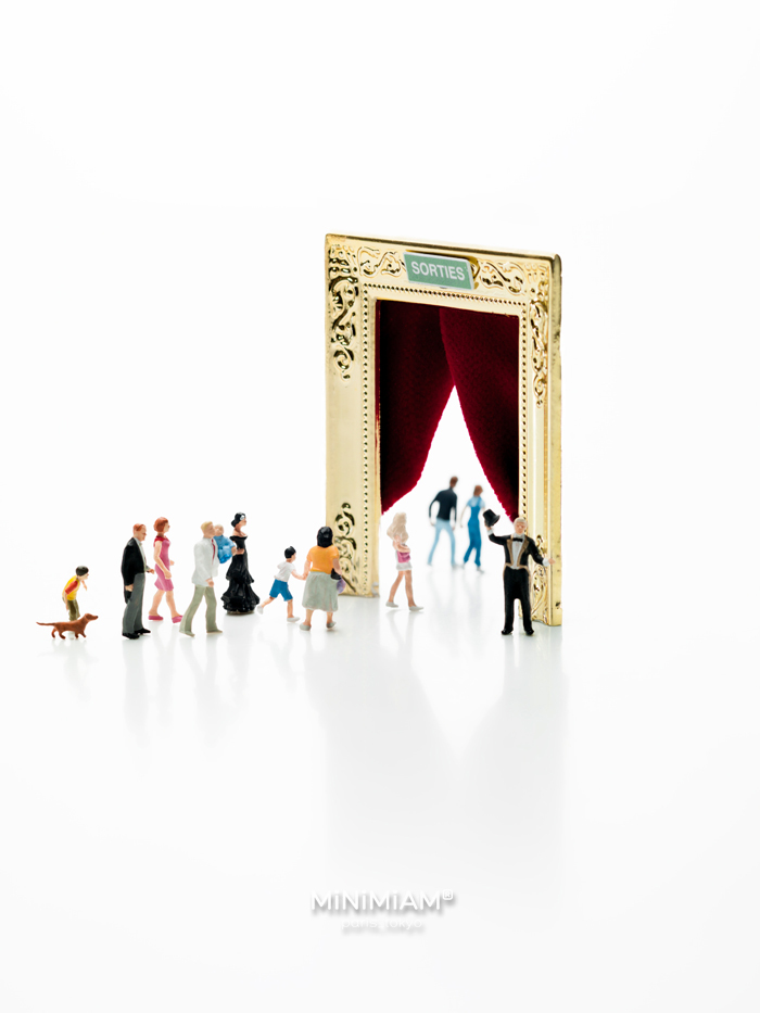 Miniature figures entering a door frame with a red curtain in the tiny world of creative miniatures.