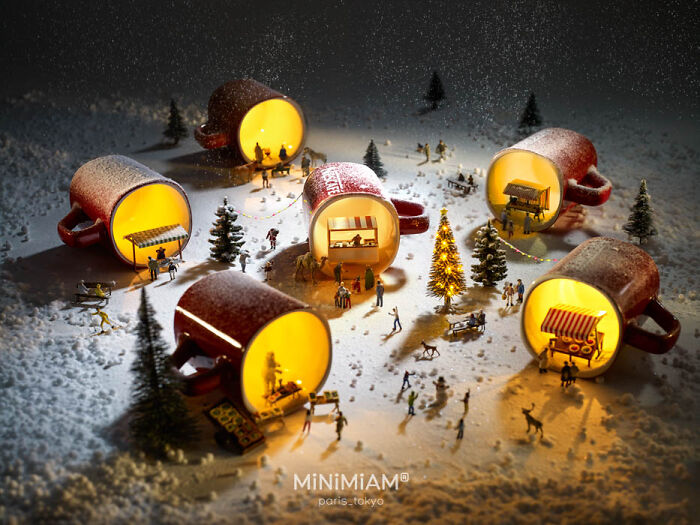 Miniature winter scene with tiny figures inside glowing mugs, created by a creative duo.