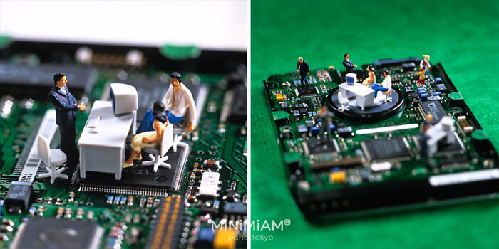 Miniature office scene on a circuit board, created by a creative duo, showing tiny figures around a desk setup.