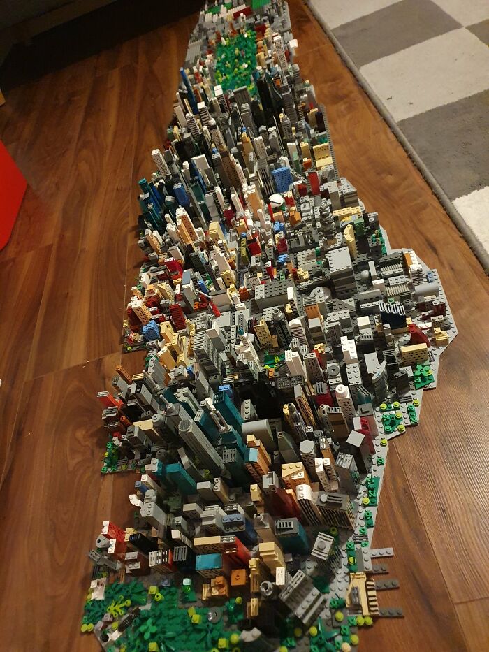 A detailed cityscape made from cool LEGO builds on a wooden floor.