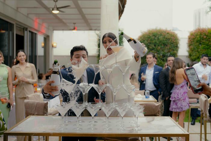 Bride and groom pouring champagne over a glass tower at an elegant wedding celebration.