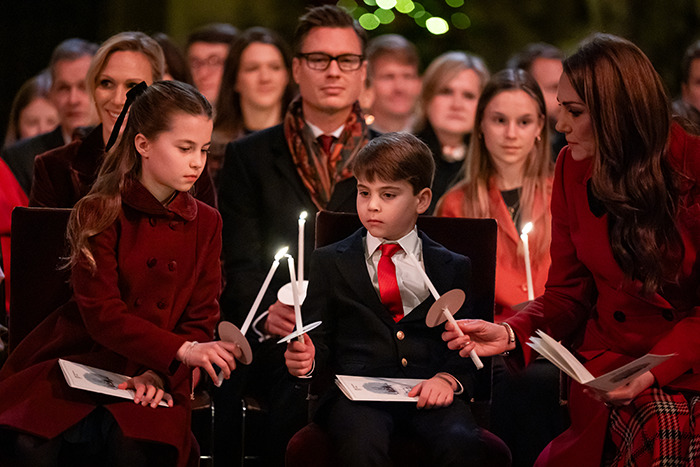 Princess Kate with her children, holding candles, dressed in festive attire.