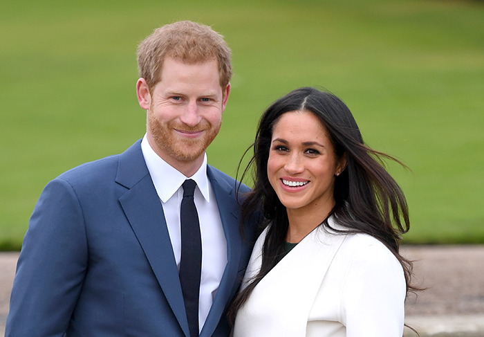 Prince Harry and Meghan Markle smiling outdoors.