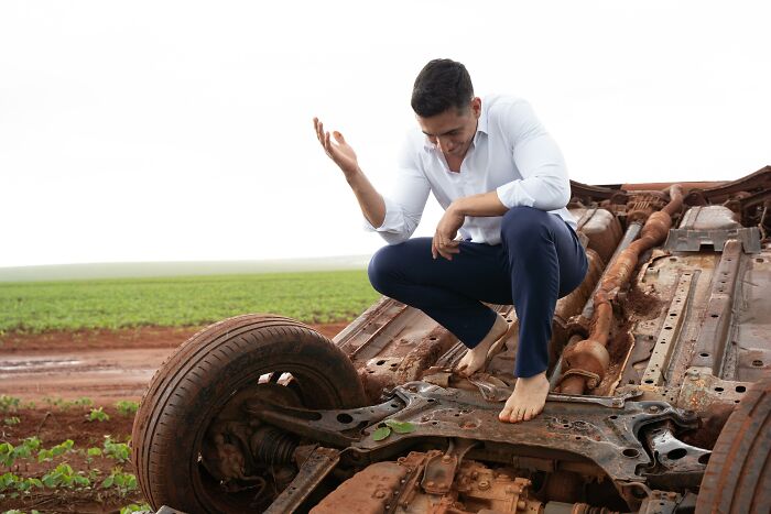 Couple takes photos at accident scene with overturned car during photo shoot trip.