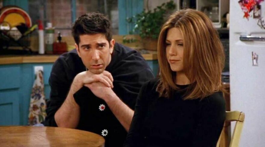 Couple sitting at a table, discussing their movie relationship poll results in a cozy kitchen setting in Friends.