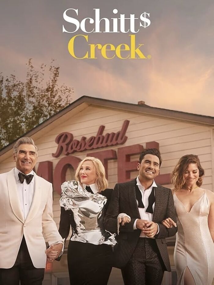 "Cast of Schitt's Creek posing in front of Rosebud Motel, related to canceled TV shows continuation or reboot."