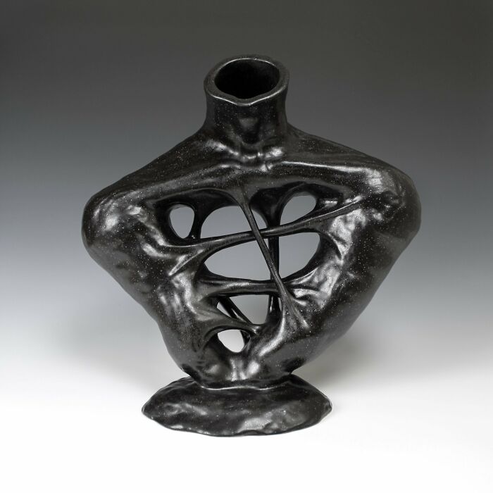 Surreal ceramic art sculpture by Jackson Shaner, featuring twisted, abstract shapes in a glossy black finish.