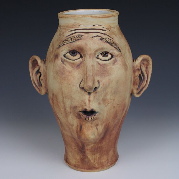 Surreal ceramic art vase with human face, featuring expressive eyes and ears.