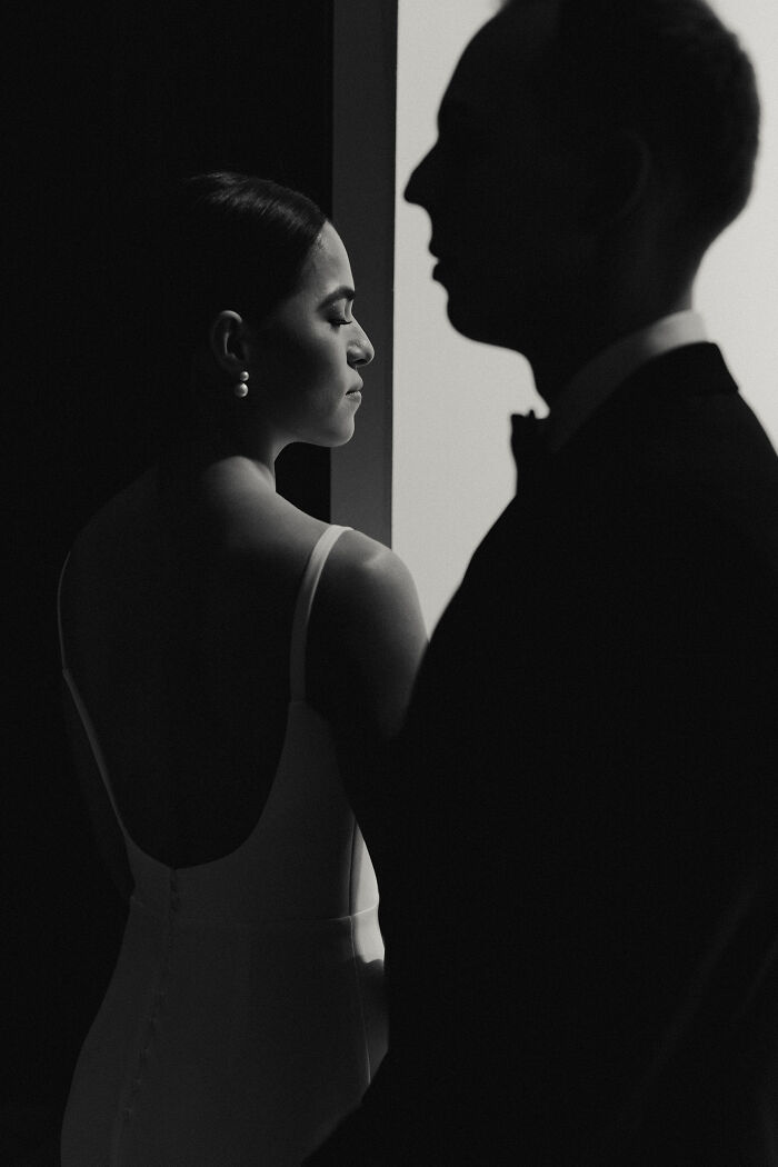 Elegant wedding photo of a bride in a white dress with pearls and a groom in silhouette, capturing a timeless moment.