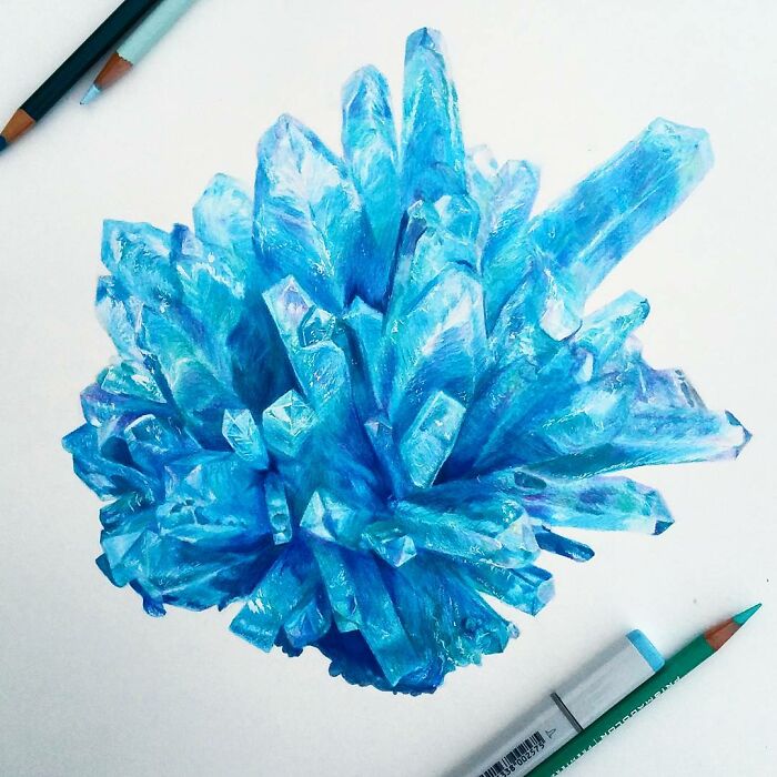 Hyper-realistic pencil drawing of a vibrant blue crystal formation, with colored pencils nearby.