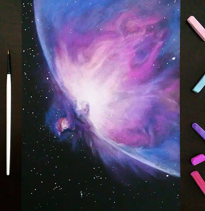 Hyper-realistic pencil drawing of a vibrant purple nebula with surrounding pastel sticks and a brush on a dark surface.