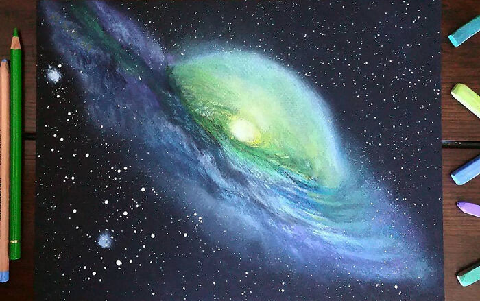 Hyper-realistic pencil drawing of a galaxy with vivid green and blue swirls, surrounded by chalks and pencils.