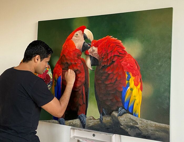 Brazilian artist painting vibrant parrots on canvas, transforming feathers into fine art.