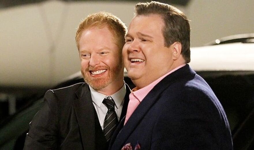 A smiling couple from a movie, dressed in formal attire, representing a relationship for a poll in Modern Family.