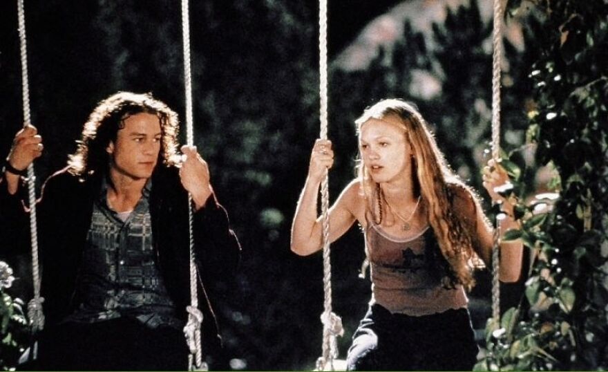 Couple sitting on swings, having a conversation in a dimly lit, outdoor setting in 10 Things I Hate About You.