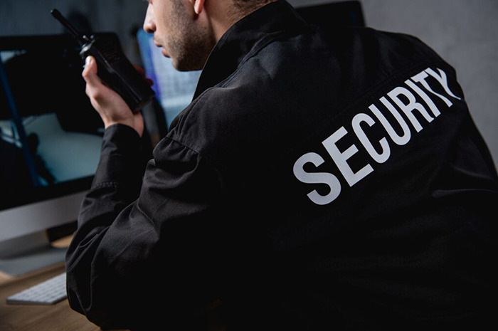 Security expert holding a radio, seated in front of a computer, emphasizing security insights.