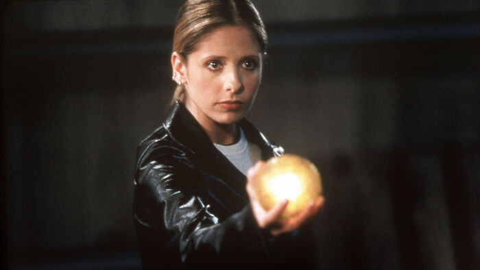 A woman in a leather jacket holds a glowing orb, sparking fascinating fan theories.