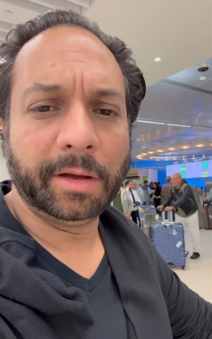 Wedding photographer, Pervez Taufiq, at airport, with people and luggage in the background.