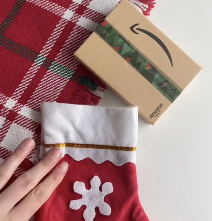 Red knitted Christmas stockings labeled Kelly, Alex, and Liam, hanging on a festive garland, perfect for gifting a gift card.