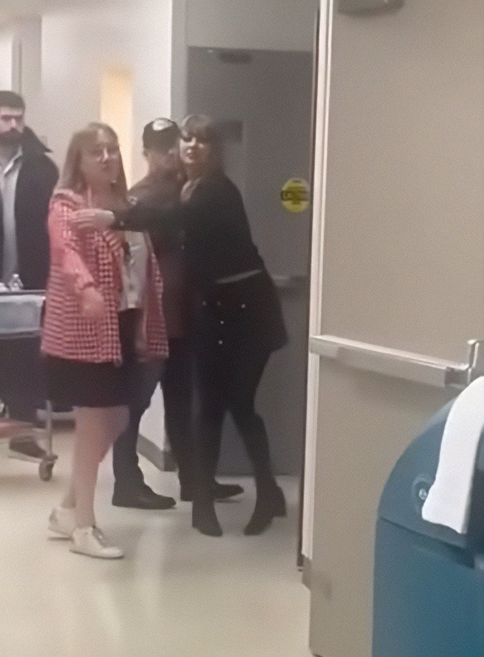 Taylor Swift in a hospital hallway, interacting with team members during a visit.