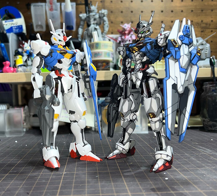 Two Gundam action figures, one unpainted and the other artistically upgraded with detailed colors, showcased on a workbench.