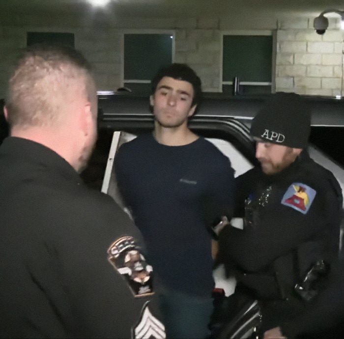 Luigi Mangione being arrested at night by police officers, related to McDonald's negative reviews.