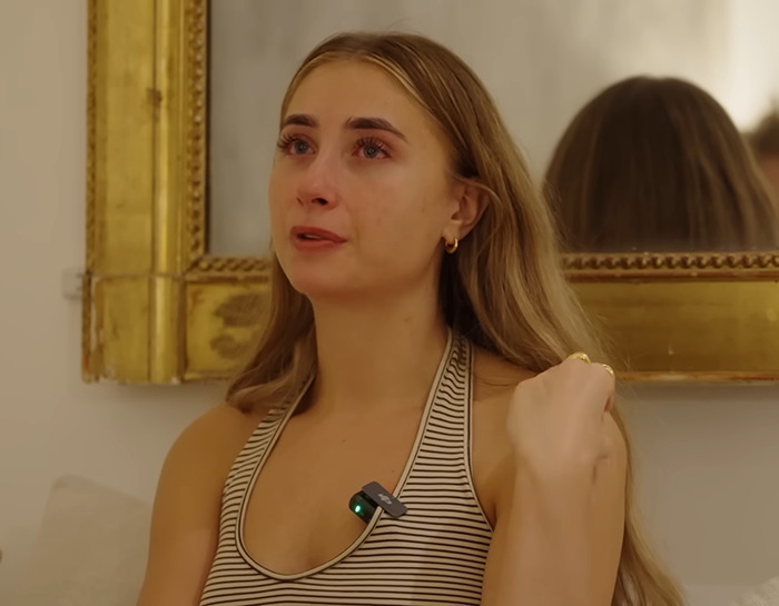 Model Lily Phillips in tears, emotional expression, wearing striped top, sitting in front of a gold-framed mirror.