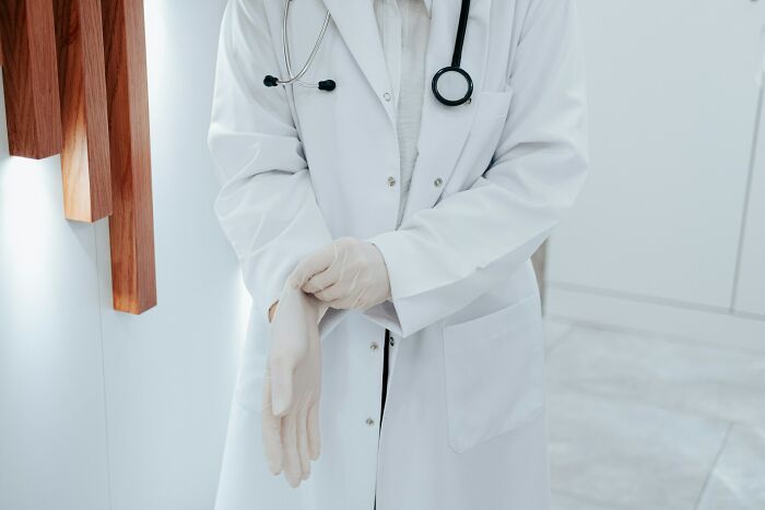 Doctor in a white coat putting on gloves, emphasizing exercise as key advice from medical experience.