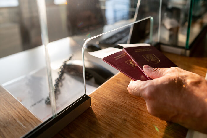 Traveler holding two passports at border control, symbolizing cringeworthy travel situations.