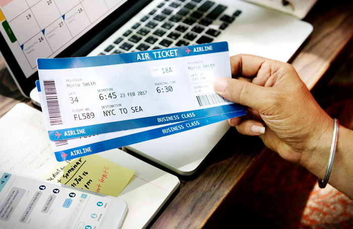 Airline ticket held by a hand, laptop and phone nearby, illustrating seat switch refusal scenario.