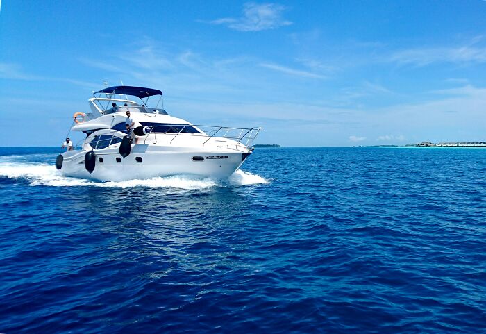 Rich kids enjoying a yacht ride on the ocean under a clear blue sky.