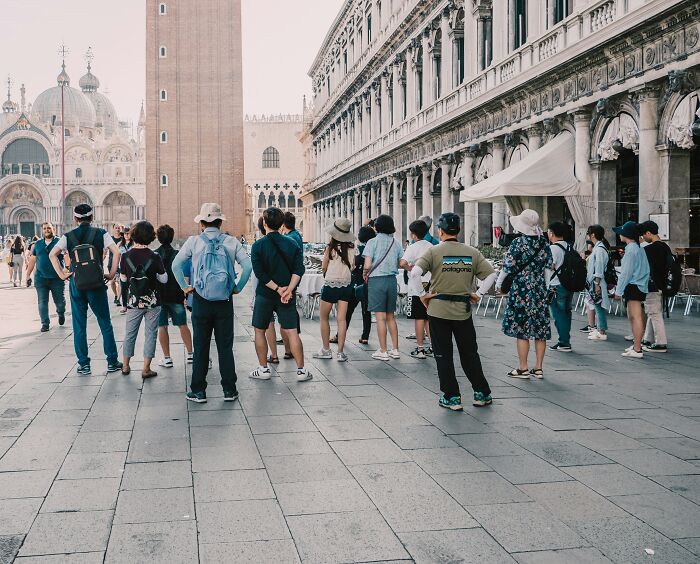 Tourists standing in a historic piazza, capturing the essence of travel moments in a busy city setting.