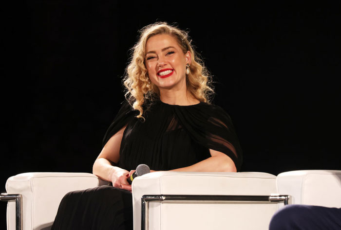 Actress from Aquaman 2 cast in a black dress, smiling during an interview.