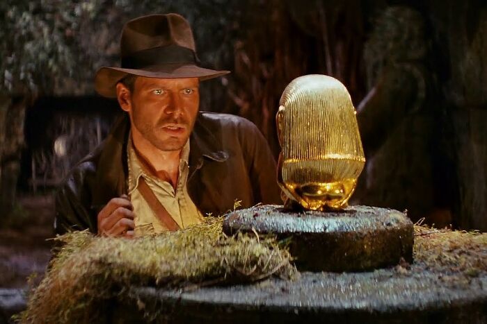 Explorer in a cave, intrigued by a golden artifact, embodying fascinating fan theories.