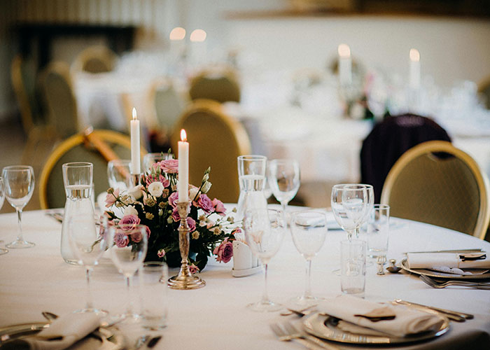 Elegant wedding table setting with floral centerpiece, candles, and place settings, capturing the ambiance of a wedding celebration.