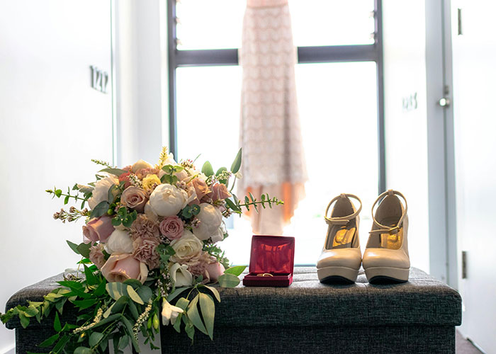 Bouquet, shoes, and dress by the window, symbolizing a wedding with keywords: attempt, bride, wedding date.