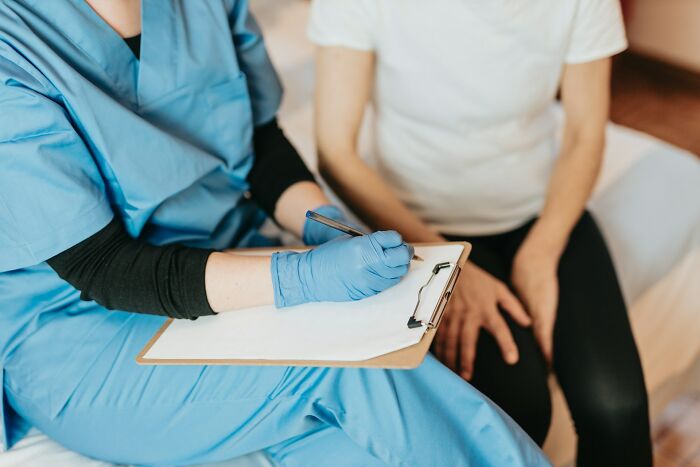 Doctor with clipboard advising patient on exercise benefits.