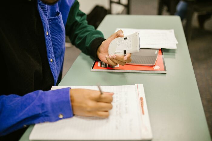 A person using a calculator and writing notes, symbolizing moments babysitters notice unusual childhood experiences.