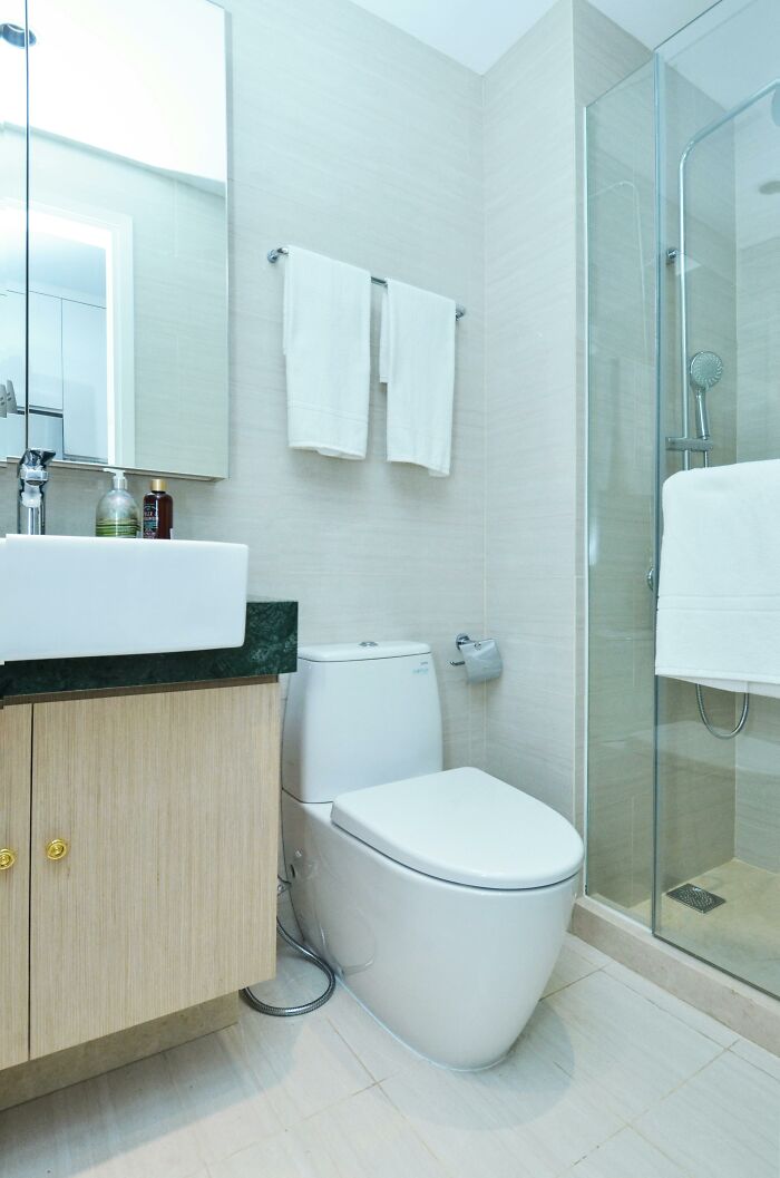 Modern bathroom with a glass shower, a white sink, and a toilet.