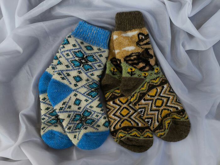 Two colorful pairs of knitted socks with intricate patterns, possibly symbolizing unique childhood experiences.