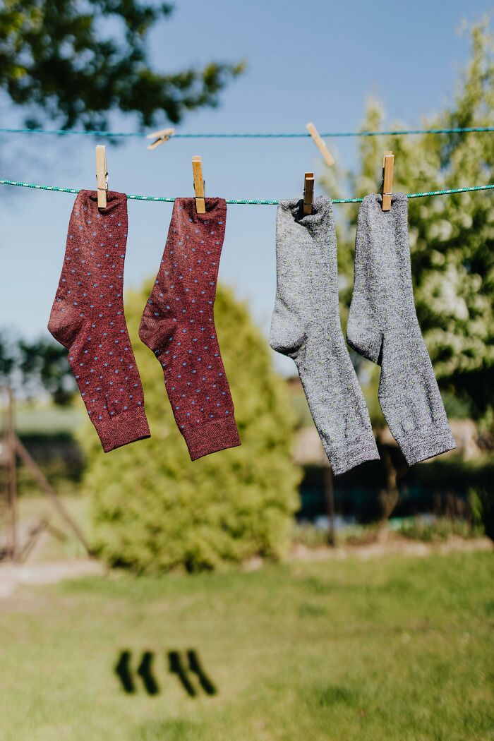 Socks hanging on a clothesline in a sunny backyard, symbolizing unique childhood moments.
